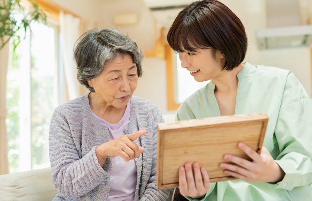 孫と写真を見るシニア女性